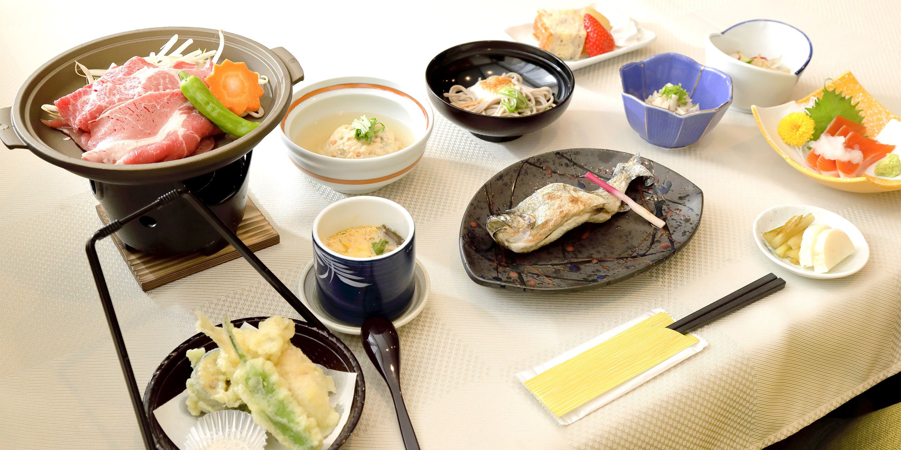 A variety of Japanese dishes including sashimi, tempura, and a hot pot.