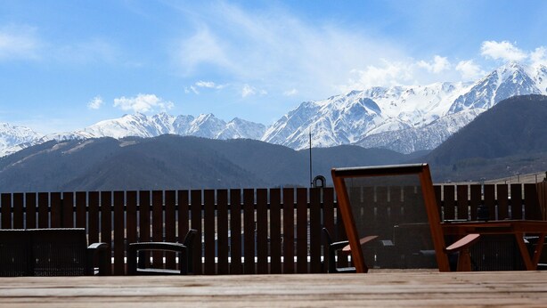 A wooden deck with outdoor furniture, a wooden fence, and a mountain backdrop. - Hotel Granjam Tsugaike (Otari)
