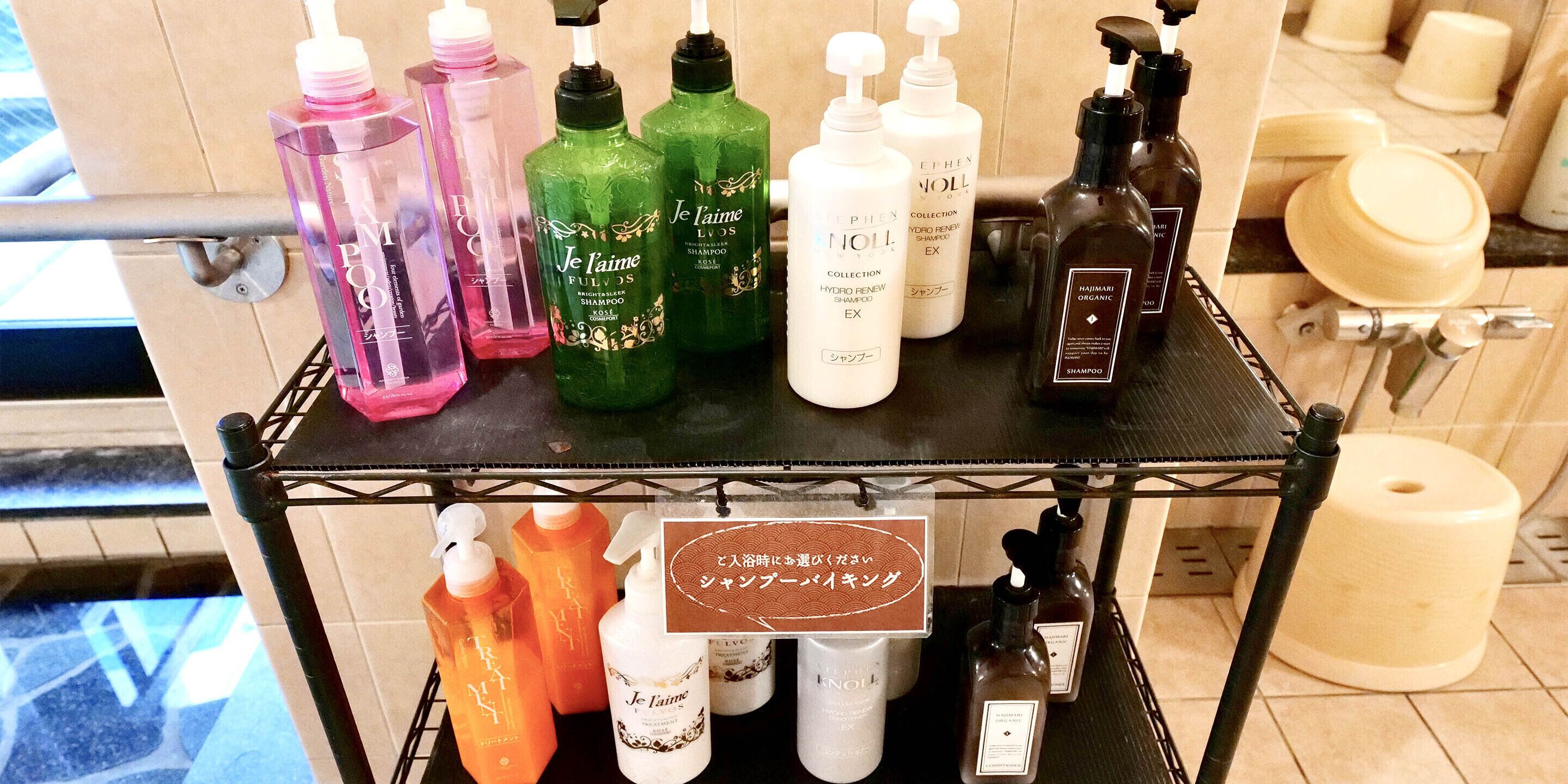 A variety of shampoos and conditioners on a metal shelf in a bathroom.
