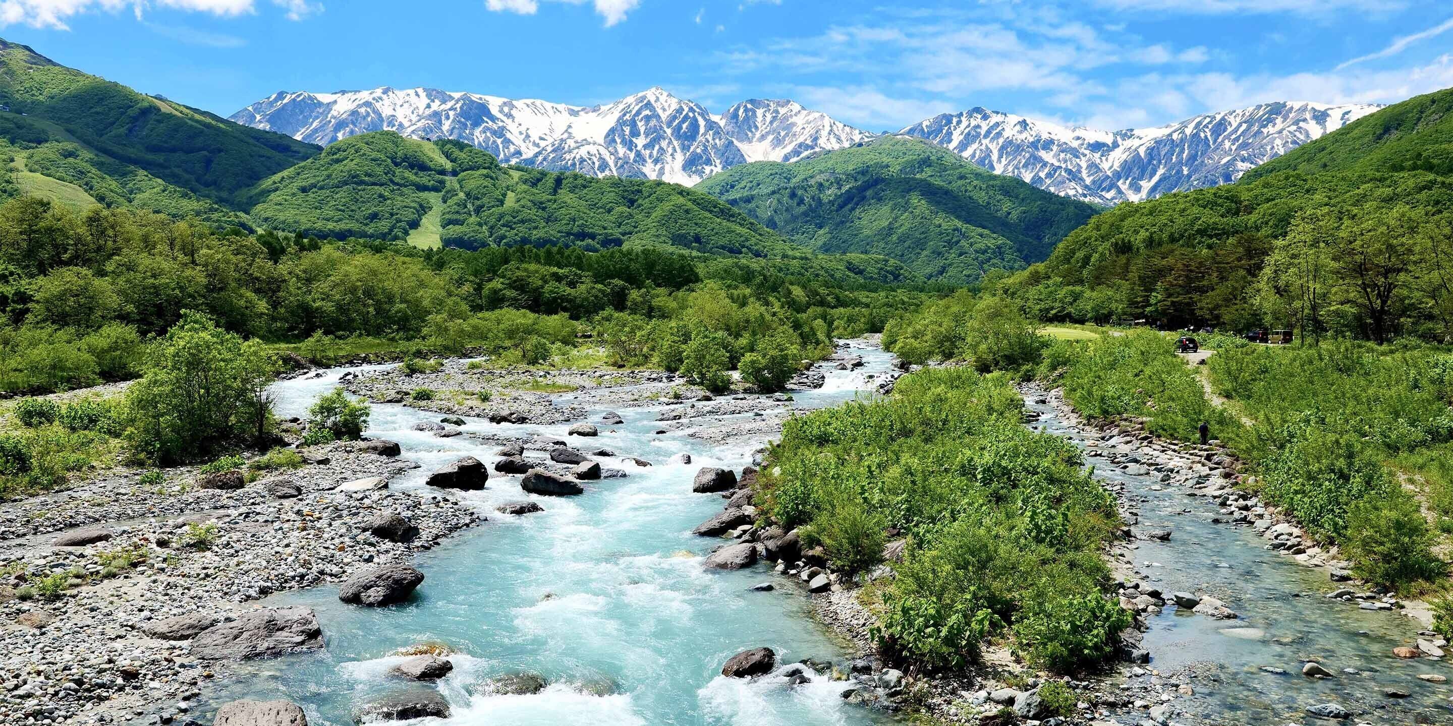 A river flowing through a valley with mountains in the background.