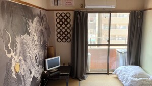 A hotel room with a large window, a bed, a TV on a small table, and a decorative wall piece. - Casa Viento Stay Inn (Hiroshima)