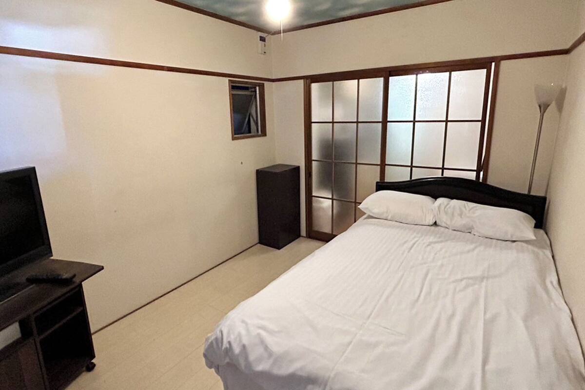 A bedroom with a bed, a TV, a wardrobe, and a sliding door.