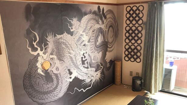 A room with a large dragon mural on the wall, a traditional Japanese lattice screen, and a window with a view of the outside. - Casa Viento Stay Inn (Hiroshima)