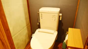 Un inodoro estándar con tanque y asiento, ubicado en un baño pequeño con piso de madera.
