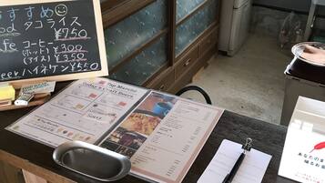 A restaurant counter with a menu, a fire extinguisher, and a refrigerator in the background.