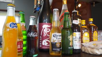 On voit une variété de bouteilles sur le comptoir d’un bar, notamment des marques comme Coca-Cola, Corona et Heineken.