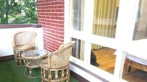 A balcony with wicker furniture, a brick wall, and a view of the interior. - Silu Homes (Lalitpur)