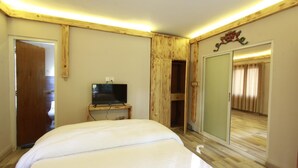 A bedroom with a bed, a television on a wooden stand, a wardrobe, and a mirror. - Silu Homes (Lalitpur)