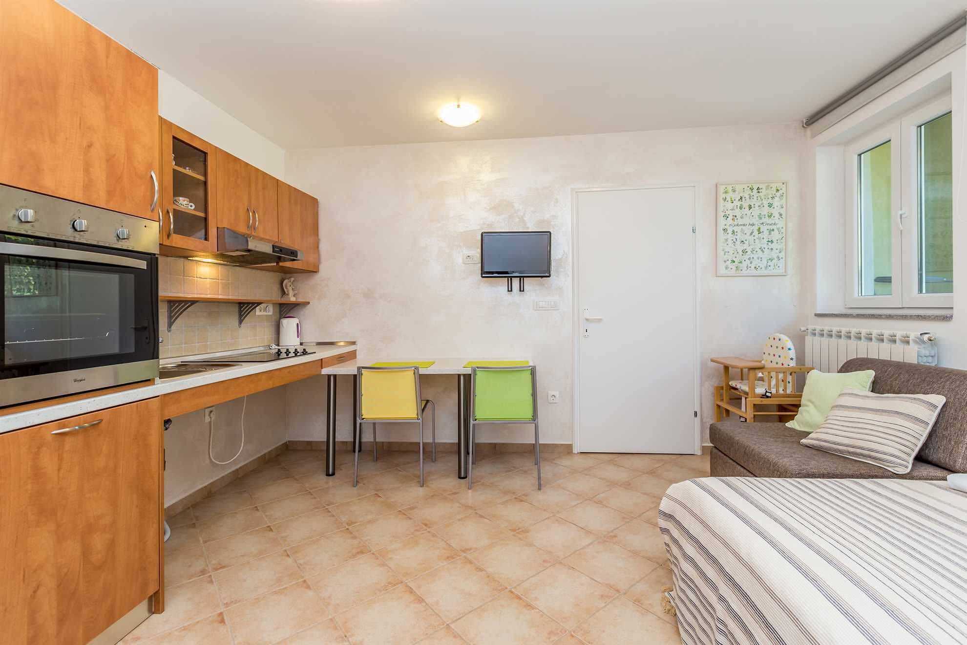 Une cuisine compacte avec des meubles en bois, un four encastré et un petit coin repas avec deux chaises.