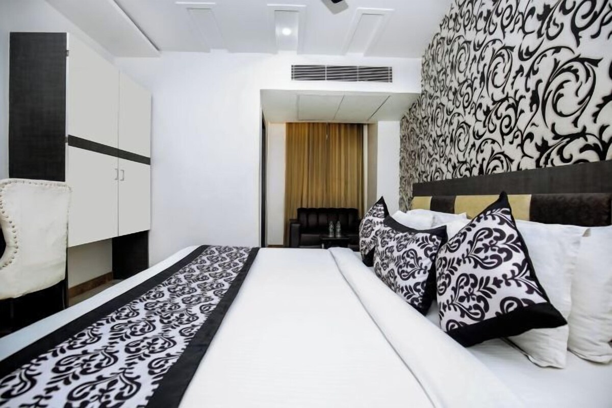 A hotel room with a bed, a wardrobe, and a patterned wall.