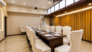 A conference room with a long table, white upholstered chairs, and a ceiling fan. - Hotel Tamanna 2 Minute Walk from Golden Temple (Amritsar)