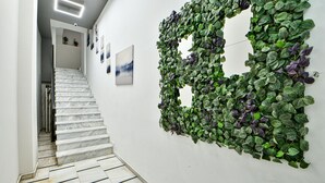 A staircase with white marble steps and a wall covered with green foliage. - Flowers Of Athens - Boutique Aparthotel (Athens)