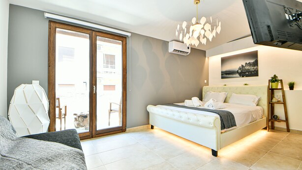 A bedroom with a bed, a sofa, a ceiling light fixture, and a wall-mounted air conditioner. - Flowers Of Athens - Boutique Aparthotel (Athens)