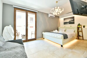 A bedroom with a bed, a sofa, a ceiling light fixture, and a wall-mounted air conditioner. - Flowers Of Athens - Boutique Aparthotel (Athens)
