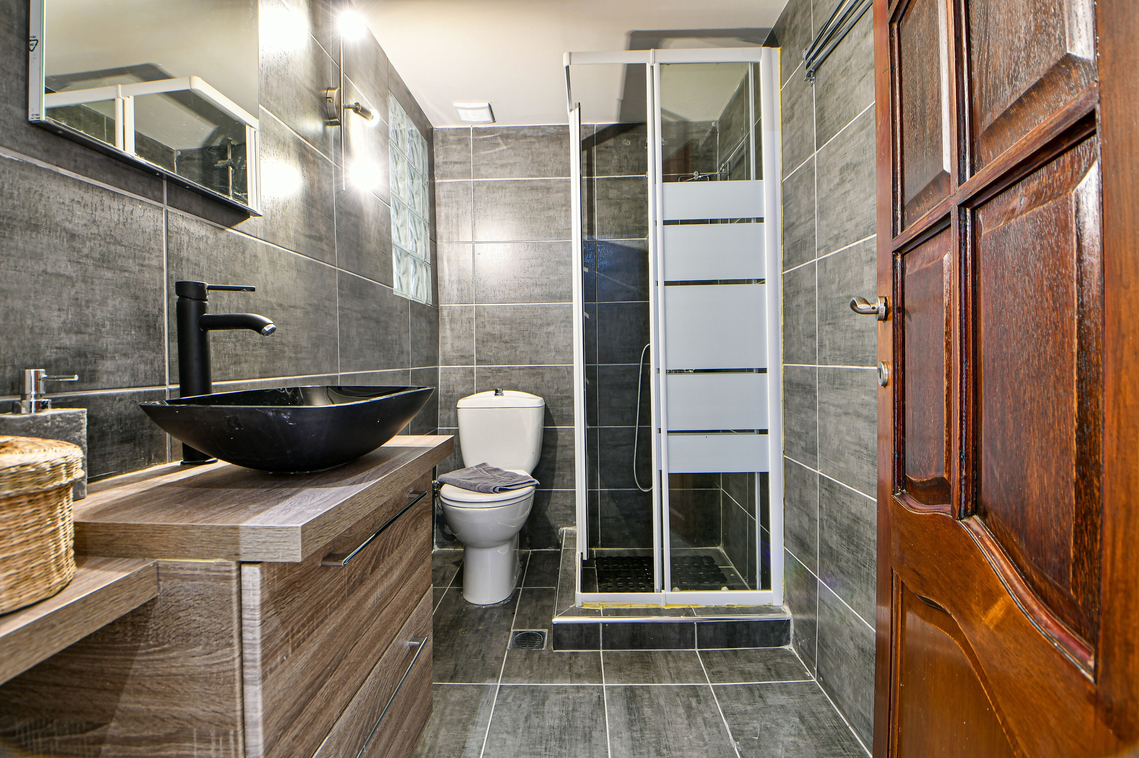 Une salle de bain moderne avec un grand lavabo noir, des toilettes et une douche à parois de verre.