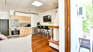 A modern kitchen with wooden cabinets, a built-in oven, and a dining area with bar stools. - Flowers Of Athens - Boutique Aparthotel (Athens)