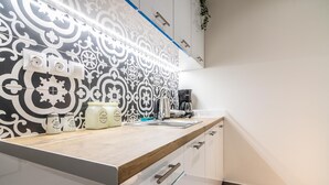 Een moderne keuken met een betegelde achterwand, een houten aanrechtblad en een koffiezetapparaat.