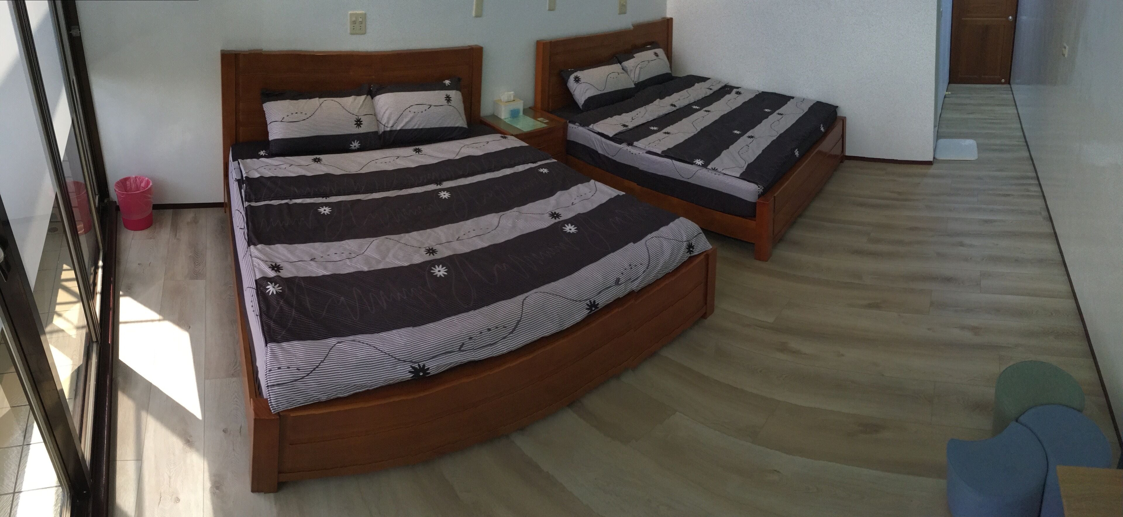 Une chambre avec deux lits en bois, chacun agrémenté de draps à rayures et de motifs en forme d’étoiles. On y trouve une petite poubelle et une table de chevet en bois sur laquelle est posée une boîte de mouchoirs.