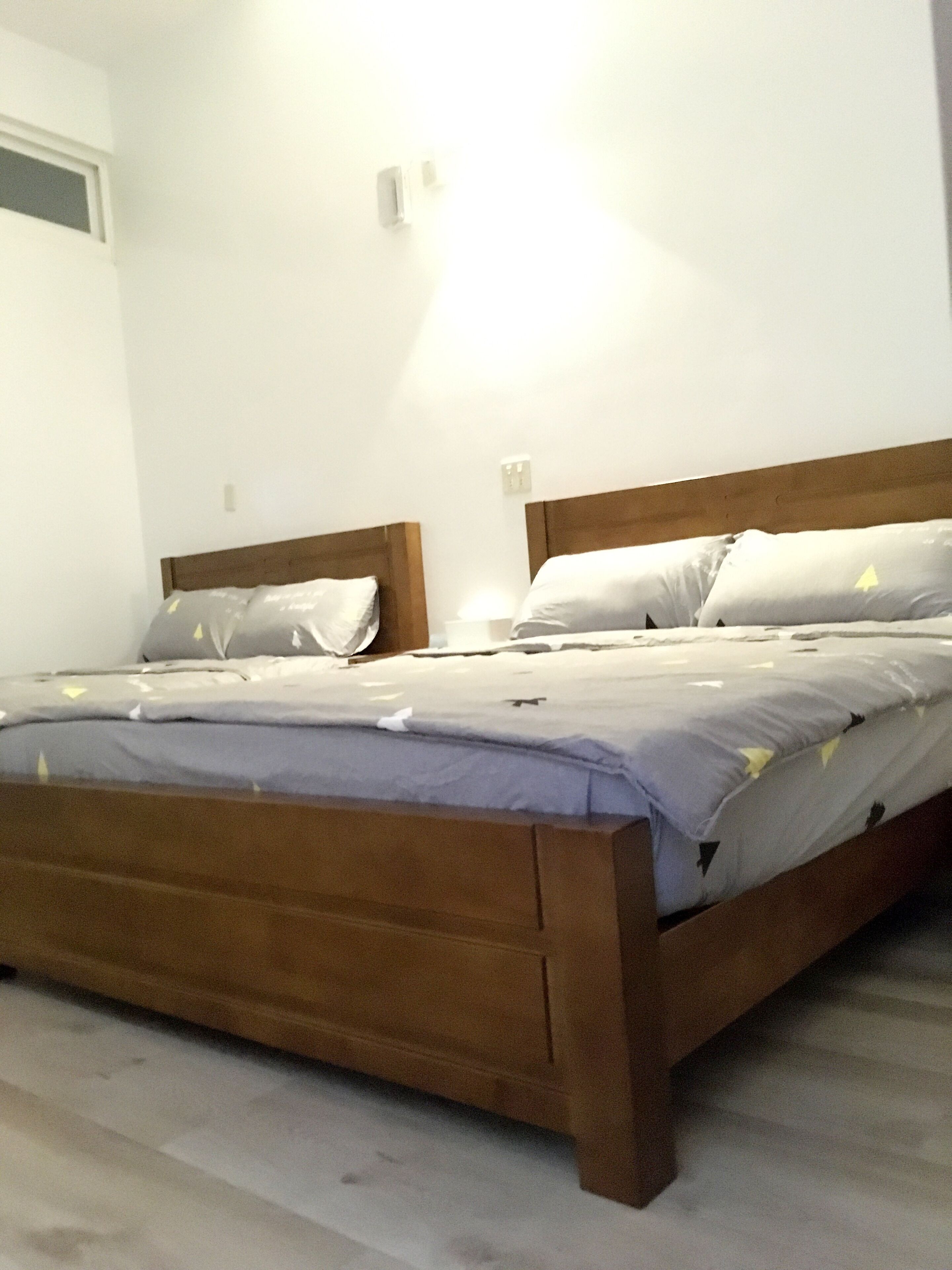 A single bed with a wooden headboard and a grey bedspread.