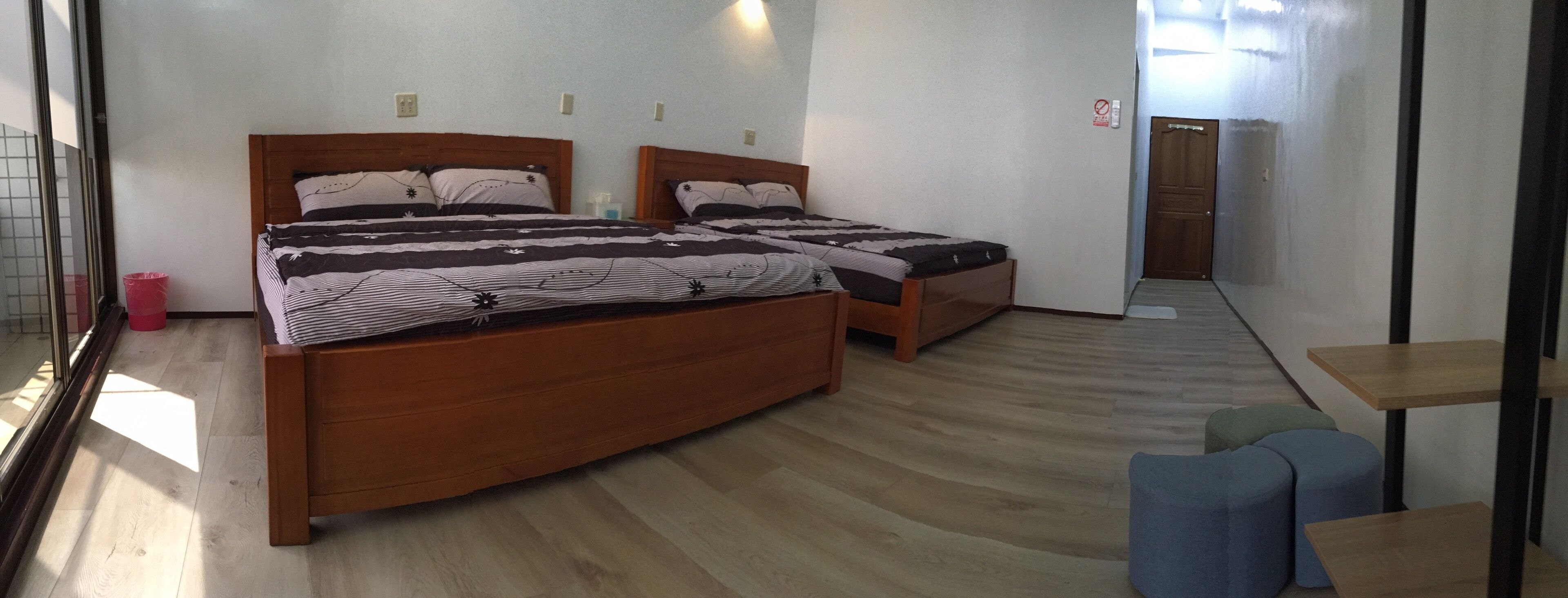 Una habitación de hotel con dos camas de madera, una mesita pequeña y un banco.