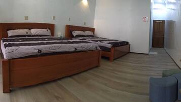 Una habitación de hotel con dos camas de madera, una mesita pequeña y un banco.