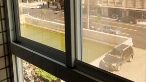 A view through a window of a street with buildings, a roundabout, and parked cars. - Reui Heng Guesthouse (Budai)