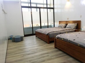 A modern bedroom with two wooden beds, a large window, and a balcony. - Reui Heng Guesthouse (Budai)