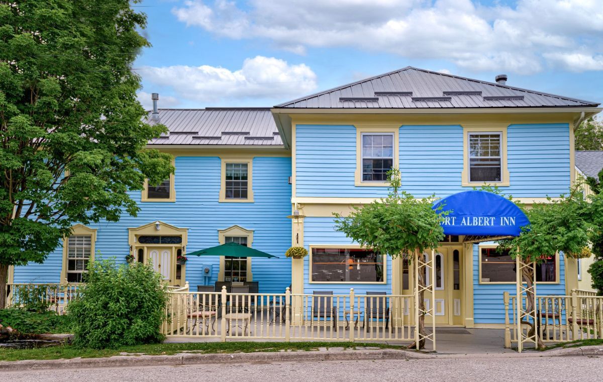 El Historic Port Albert Inn, con un estilo arquitectónico tradicional, presenta una entrada destacada con un toldo azul y una valla de piquete blanca.