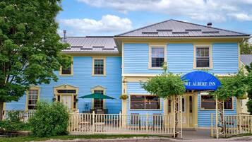 El Historic Port Albert Inn, con un estilo arquitectónico tradicional, presenta una entrada destacada con un toldo azul y una valla de piquete blanca.