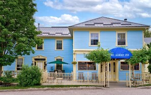 El Historic Port Albert Inn, con un estilo arquitectónico tradicional, presenta una entrada destacada con un toldo azul y una valla de piquete blanca.