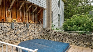 A stone wall with a blue mat, a wooden structure with a rustic appearance, and a metal railing. - Historic Inn Vacation Rental (Ashfield Colborne Wawanosh)