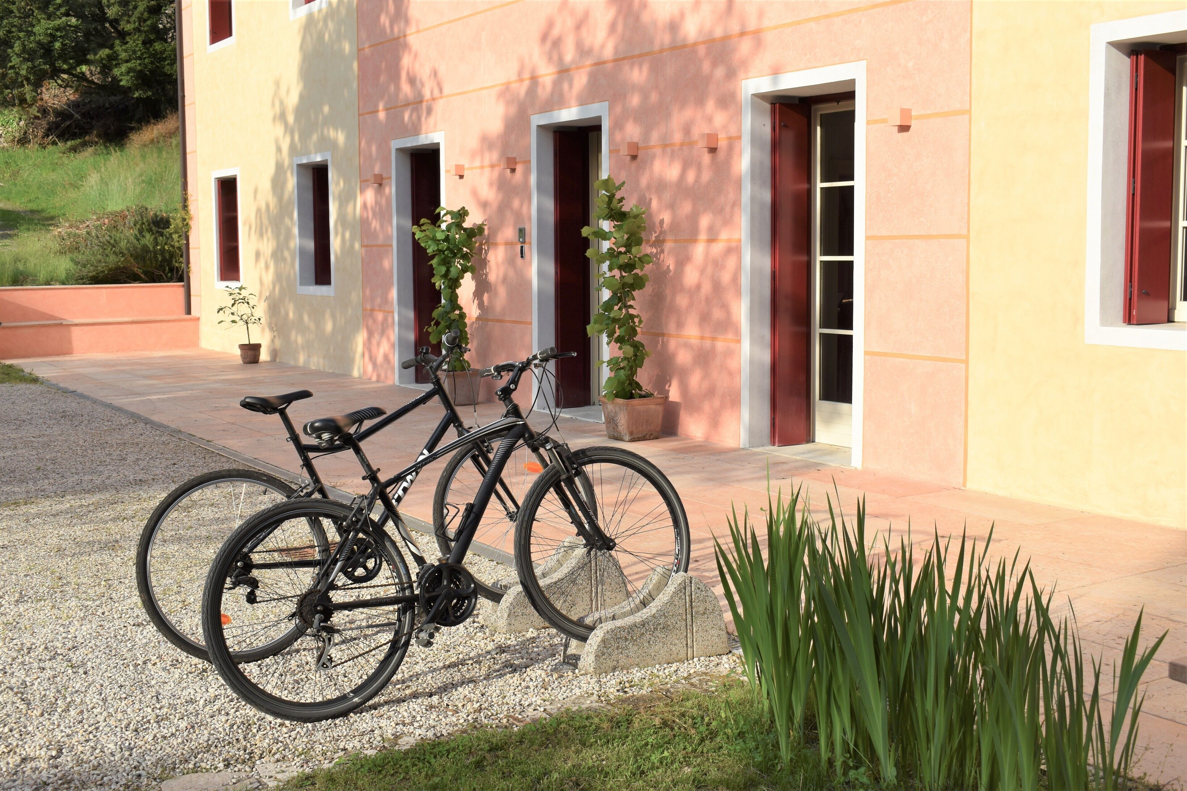 A building with a modern design, featuring a gravel driveway and a bike parked outside.