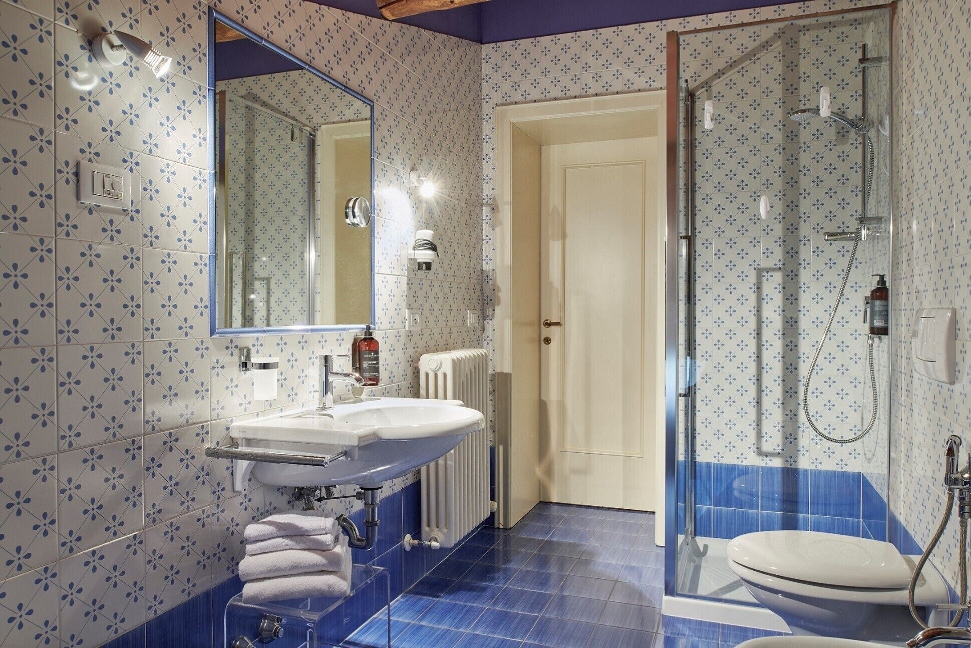 A bathroom with a white sink, a mirror, a toilet, and a shower area.