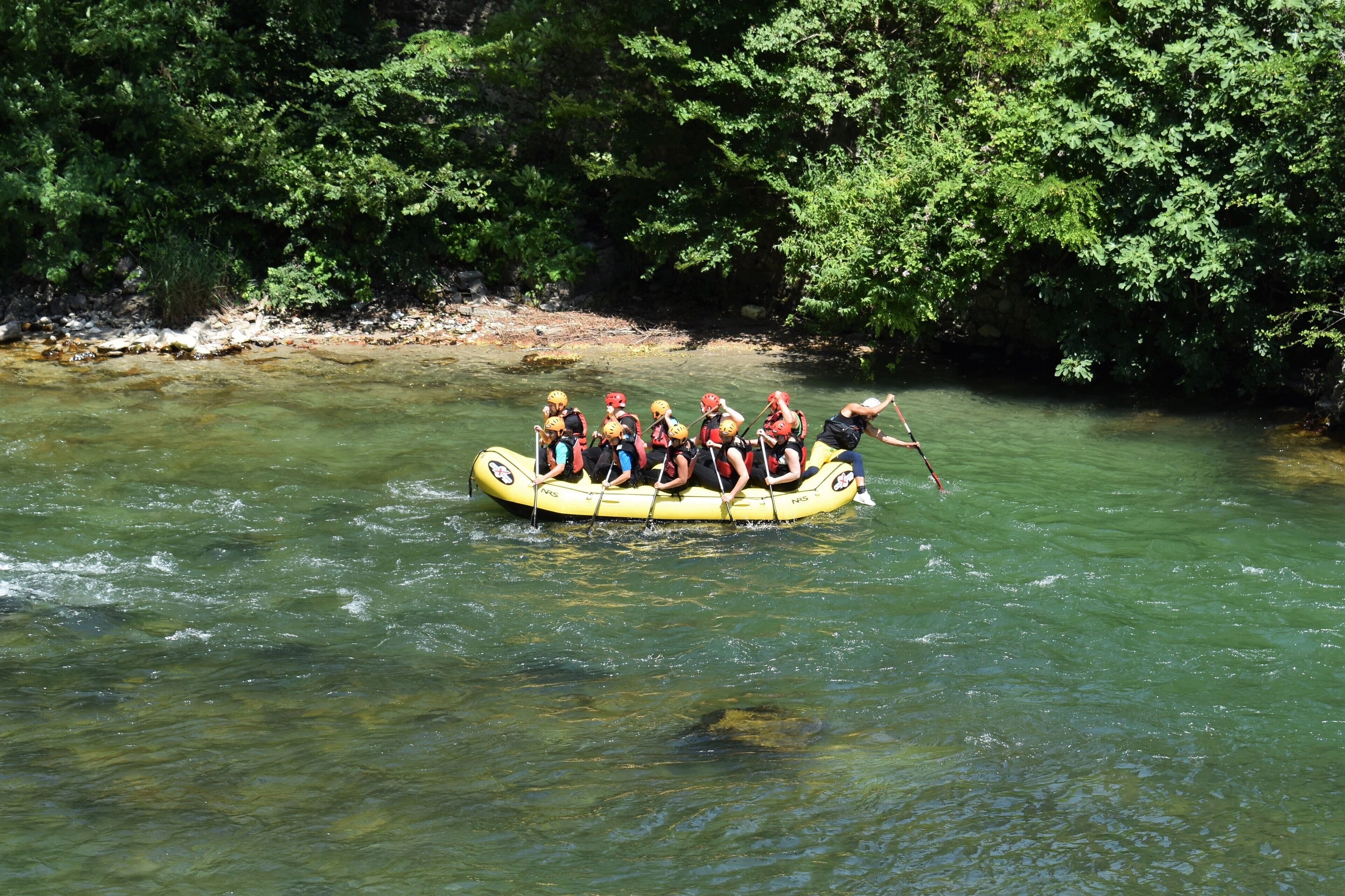 Un grupo de personas en una balsa amarilla flotando en un río rodeado de follaje verde exuberante.