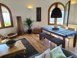 Un comedor con mesa de madera, bancos y una planta en maceta.