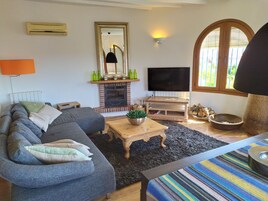 Una sala de estar con sofá, chimenea, televisor y una ventana con persianas.
