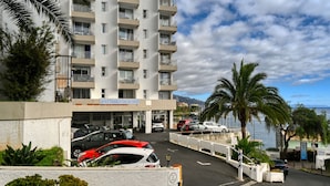 A multi-story hotel with balconies, a parking area, and a view of the sea. - Elsas Place, a Home in Madeira (Funchal)