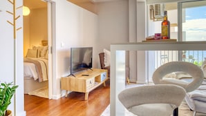 A modern living room with a wooden TV stand, a sofa, and a dining area with a table and chairs. - Elsas Place, a Home in Madeira (Funchal)