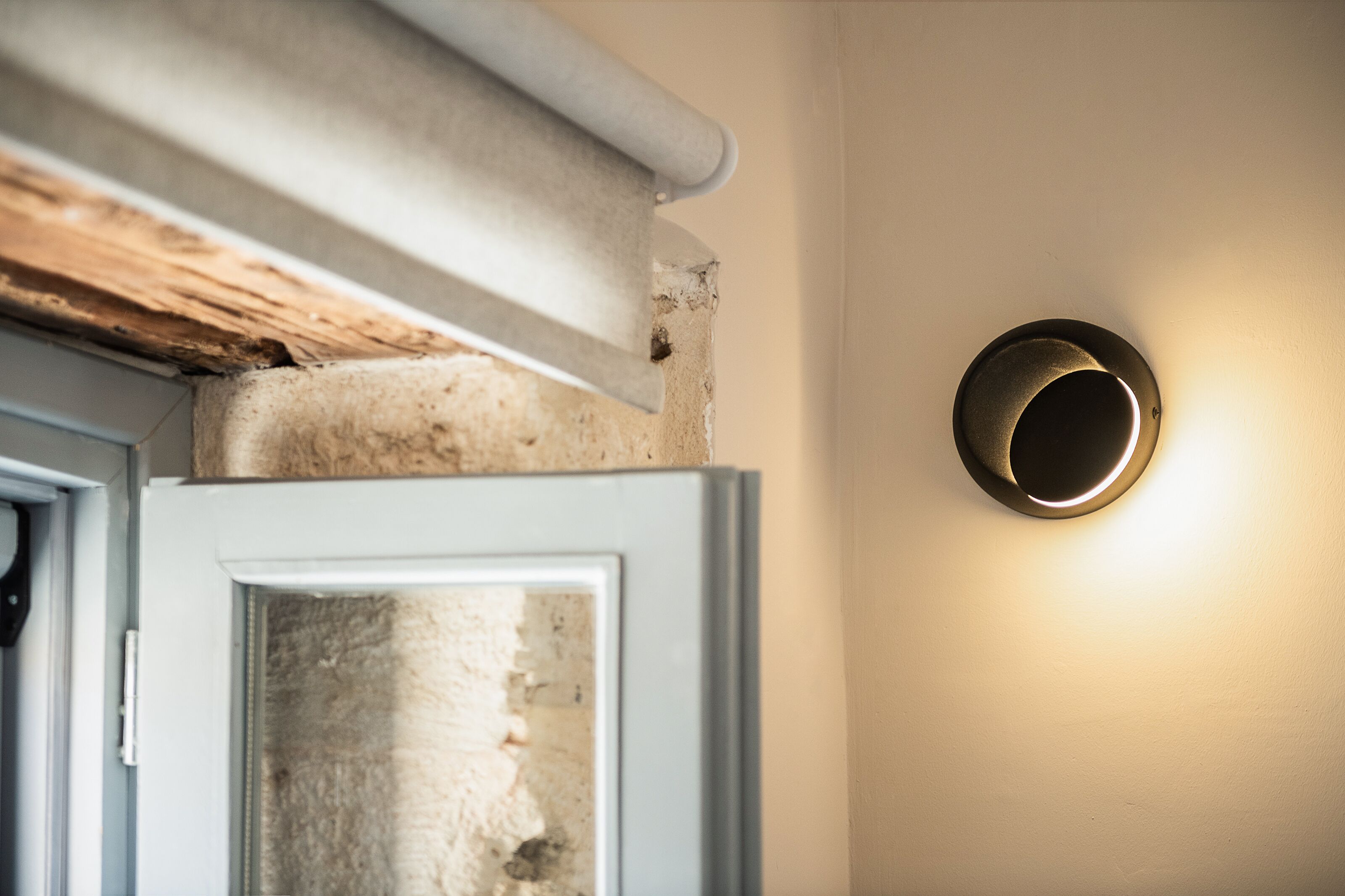 A door with a textured wall and a modern light fixture.