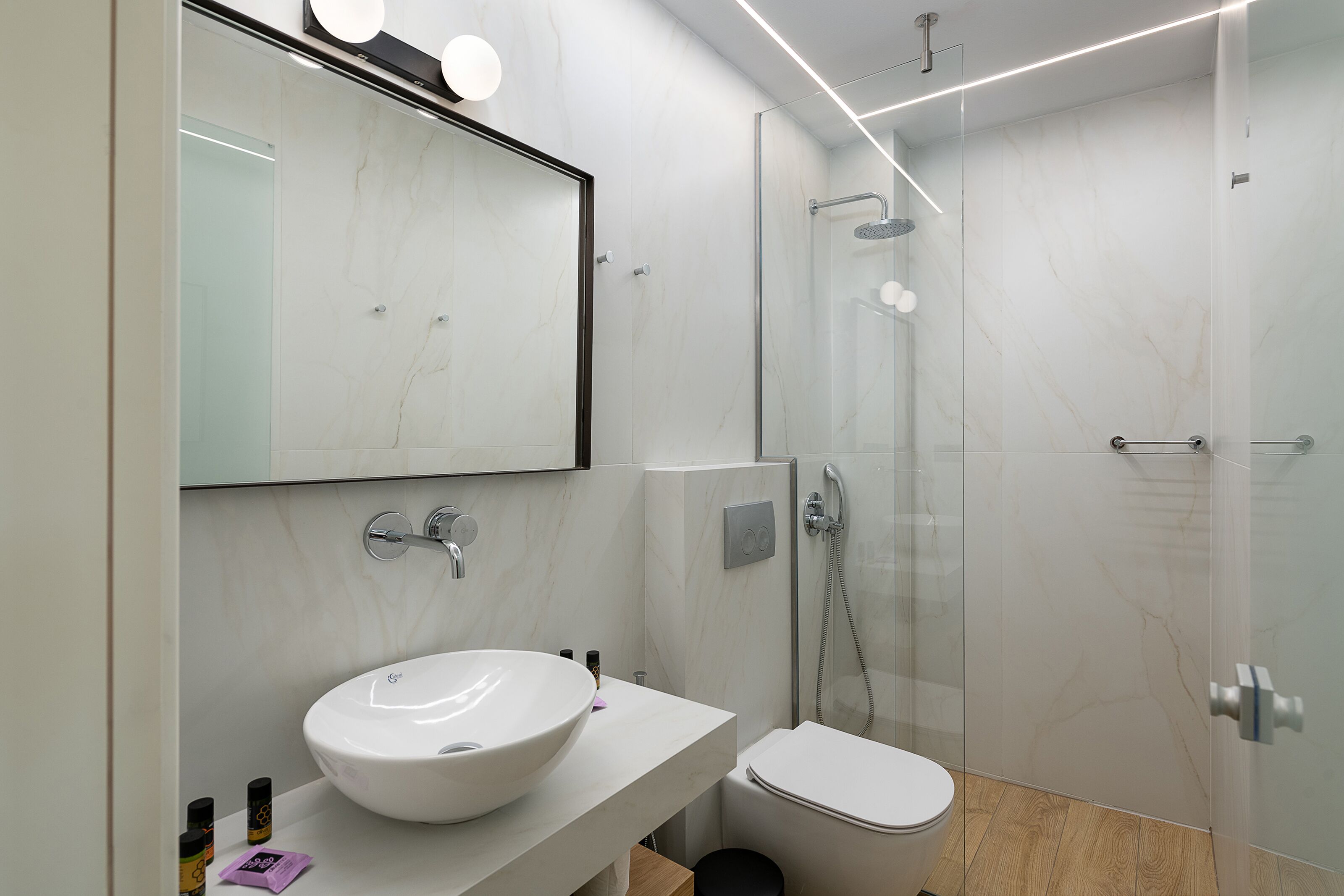 Un bany modern amb un lavabo gran de color blanc, un vàter i una dutxa amb envàs de vidre.