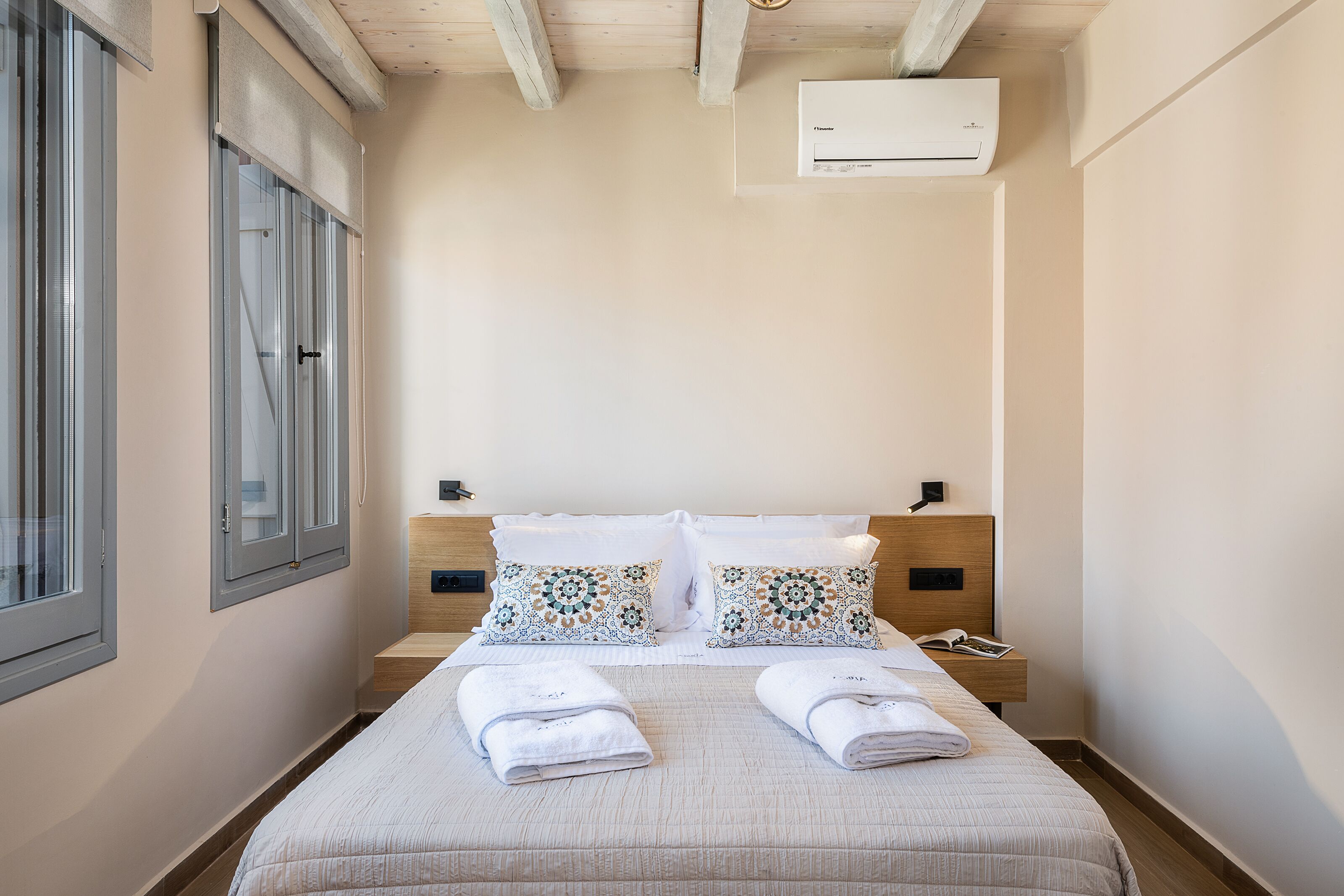 Una camera d'albergo con un letto, due comodini, una finestra e un condizionatore.