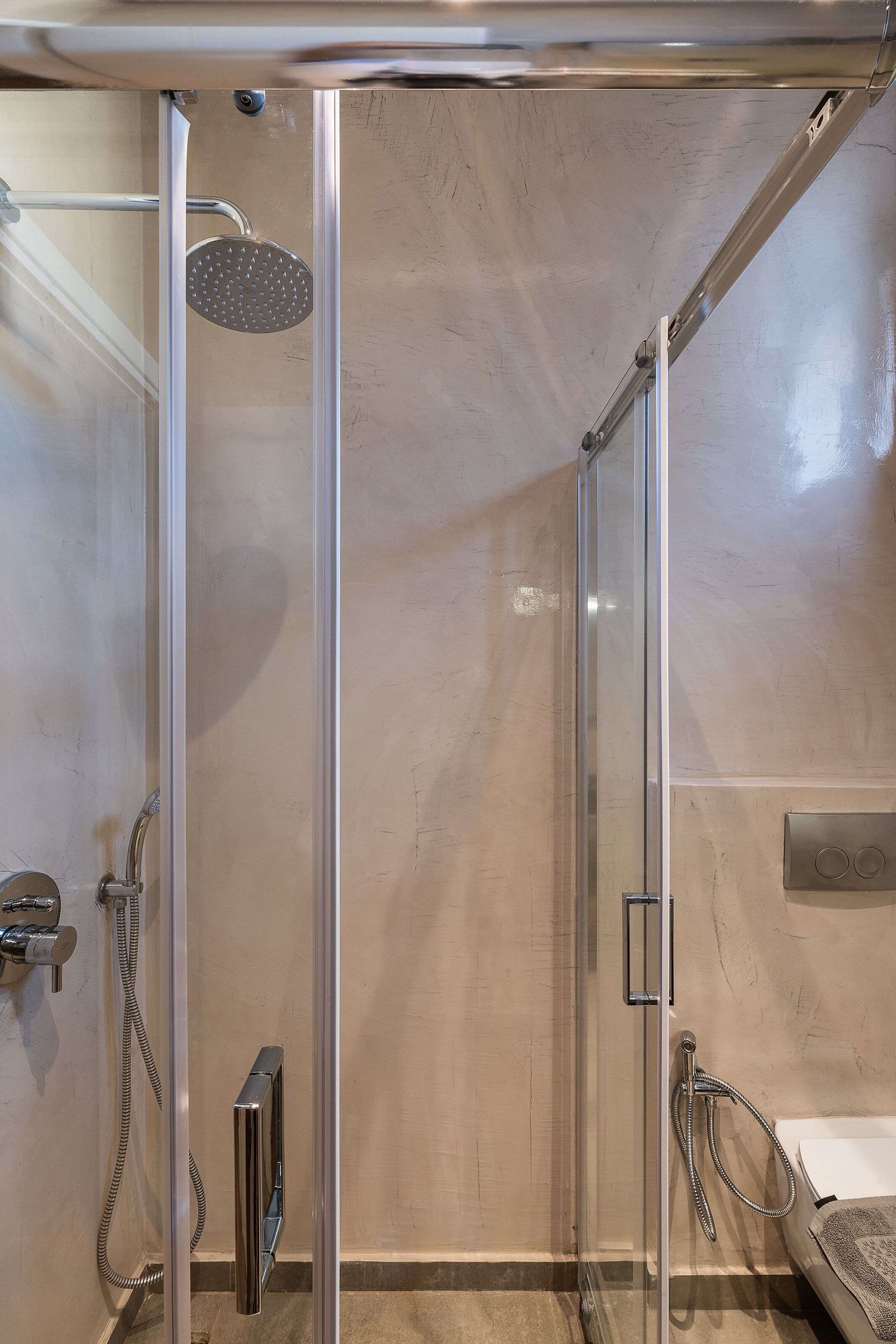 A modern shower with a glass enclosure, a handheld showerhead, and a handheld faucet.