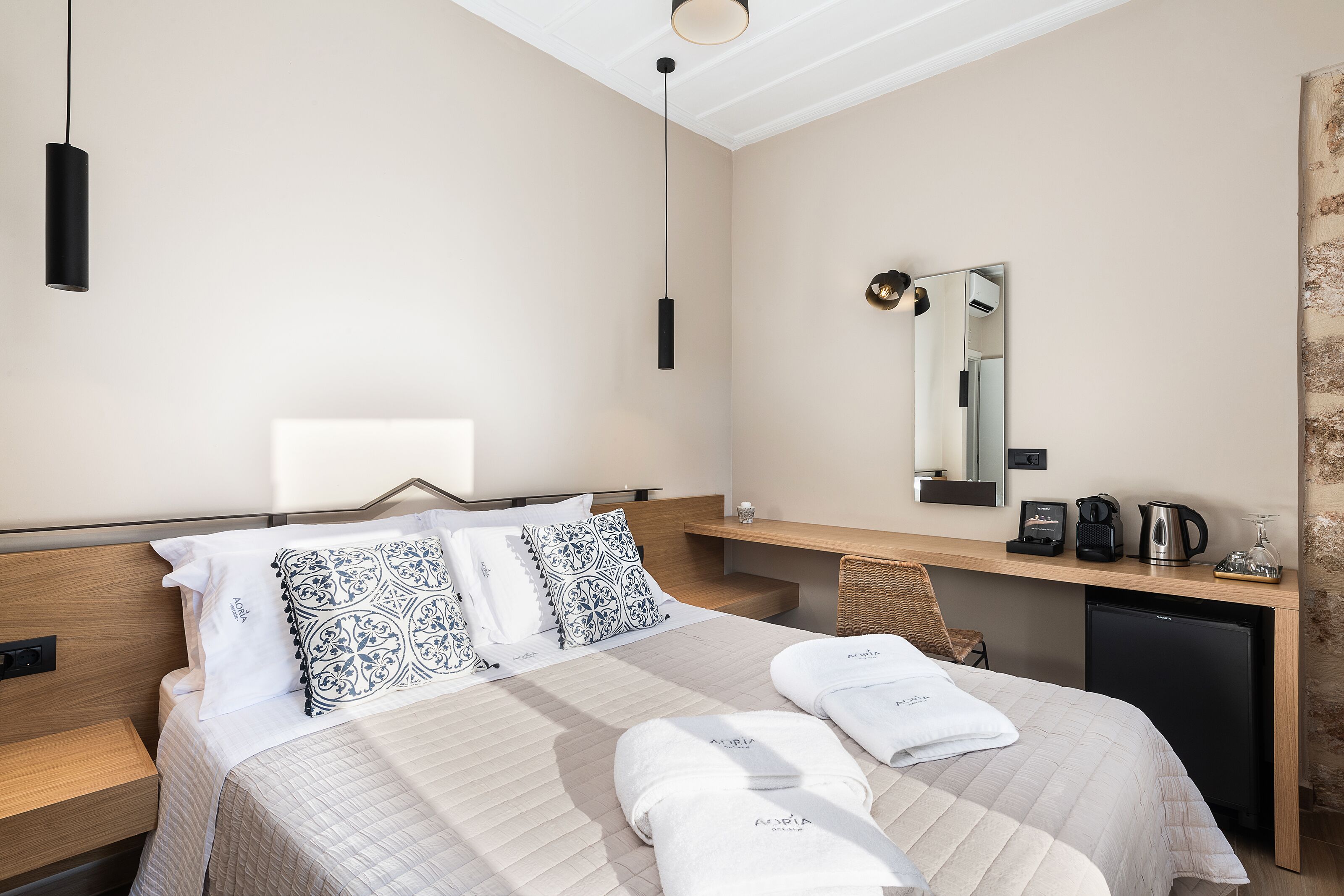 Habitación de hotel con cama, mesita de noche, escritorio y espejo.