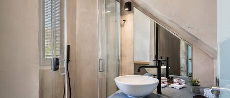 A modern bathroom with a glass-enclosed shower, a large mirror, and a white vessel sink.