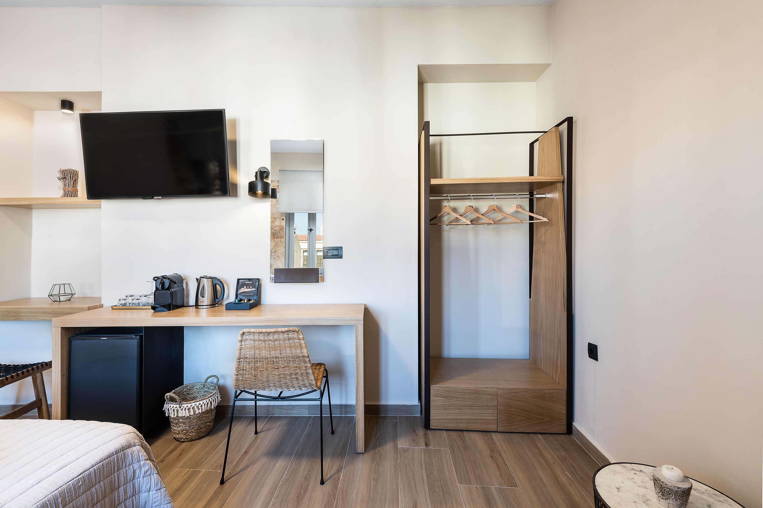 Une chambre d’hôtel comprenant un lit, un bureau avec une chaise, une télévision, un petit réfrigérateur, une armoire en bois et une salle de bain avec douche.