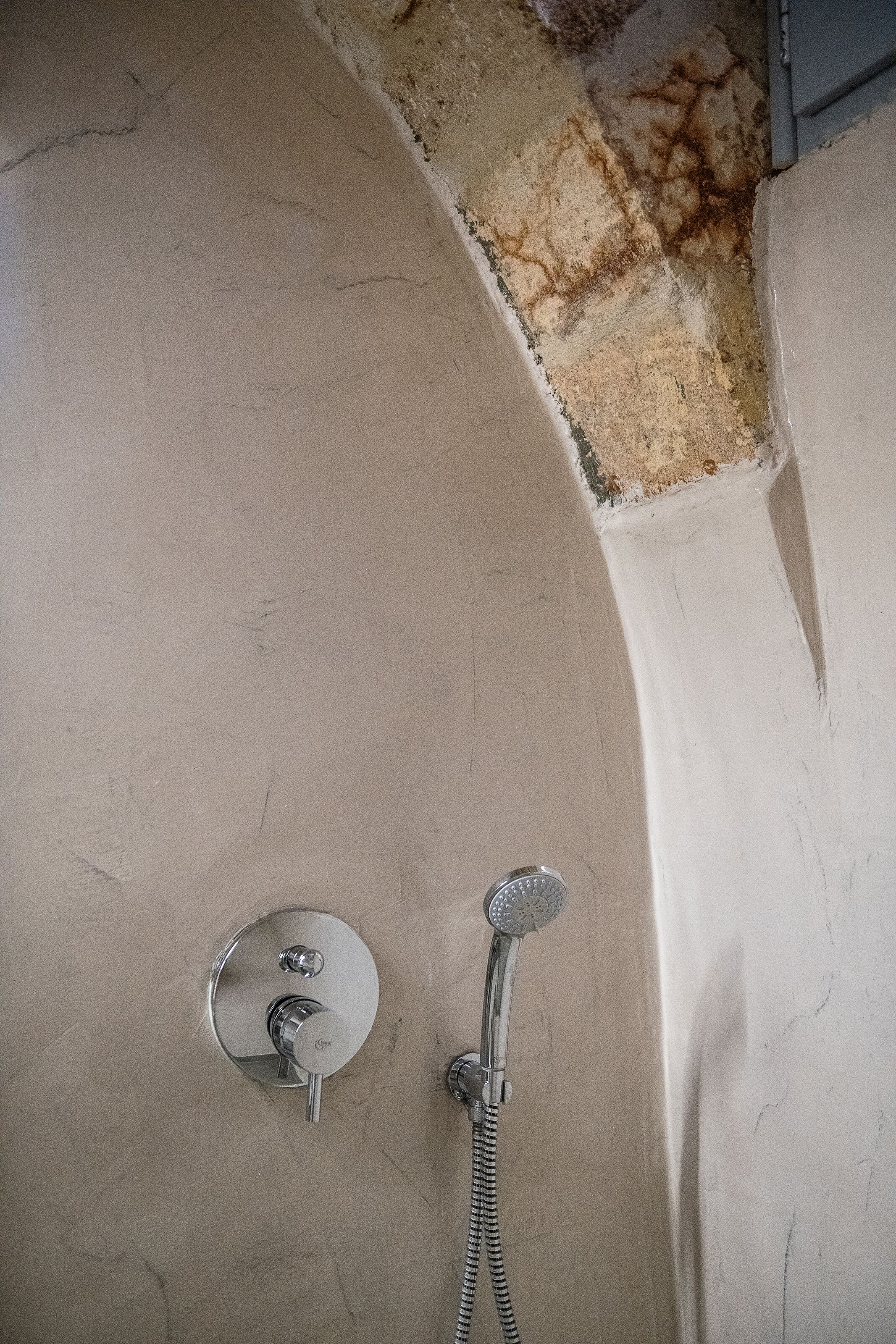 A shower area with a handheld showerhead and a wall-mounted control.