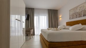 Una camera da letto moderna con un letto grande, una scrivania e un televisore a parete.