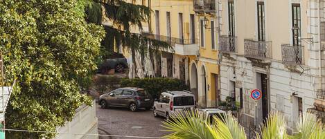 A street view with buildings, parked cars, and a no parking sign.