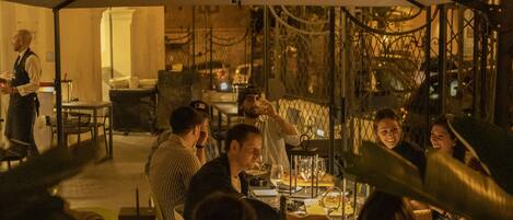 A restaurant with tables and chairs, a waiter, and guests dining.