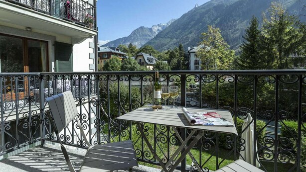 Ein Balkon mit Tisch, Stühlen und einer Weinflasche.